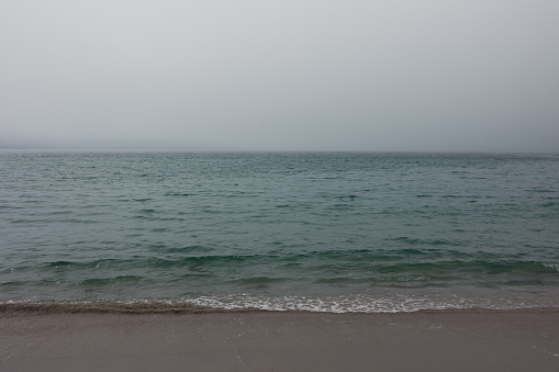The horizon line sand and sea in strong tman are all blurred. A sense of serenity and tranquility. The background color is blue and gray.
