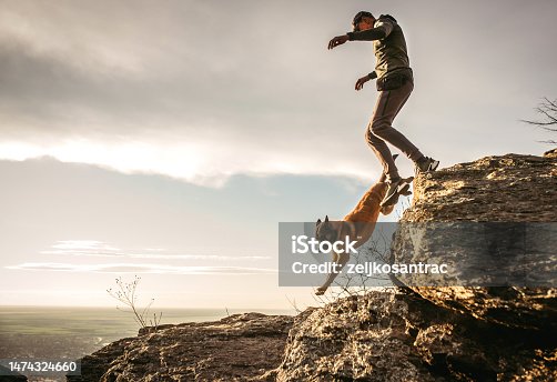 istock man hiking on the mountain with his dog during sunset 1474324660