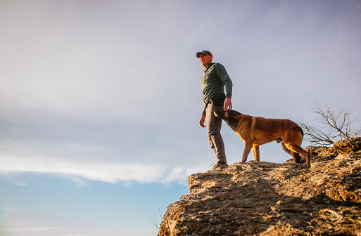 man hiking on the mountain with his dog during sunset