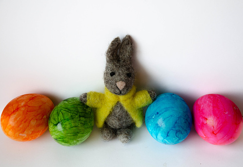 An Easter bunny made of felt with four colourful bright eggs