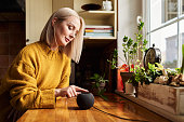 Adult woman using smart speaker on kitchen counter
