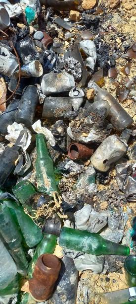 istock Overhead view of glass bottles and rusty cans, garbage lying on the field 1474332192