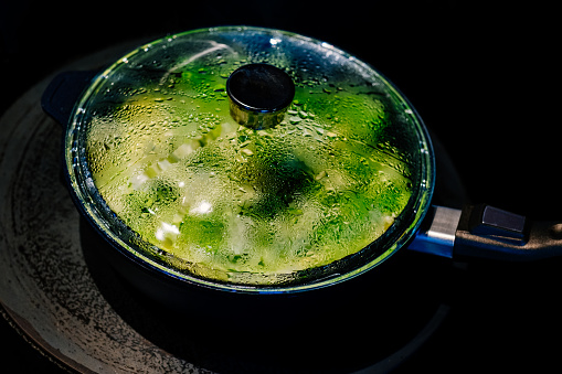 Vegetable greens steaming on a hot stove.