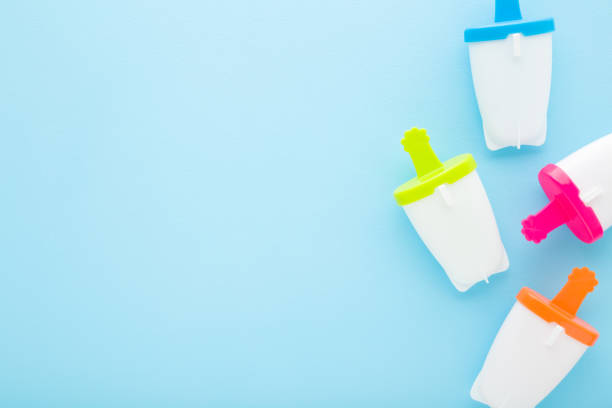 istock White plastic containers for homemade ice popsicle on colorful sticks. Light blue table background. Pastel color. Closeup. Cold sweet snack in summer. Top down view. 1474335808