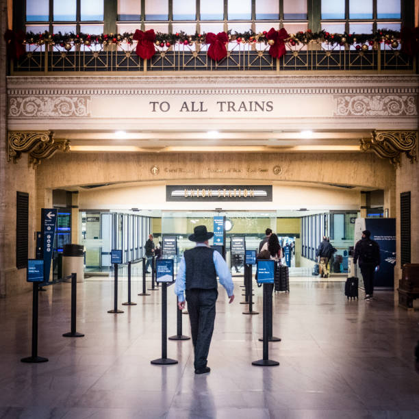 Interior of Union Station, Chicago, showing view of male Amish passenger walking towards train departure with holiday garland on railing stock photo