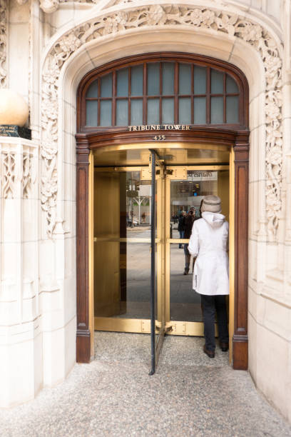 Patron entering Tribune Tower, Chicago, through heavy revolving gold doors with reflections. stock photo