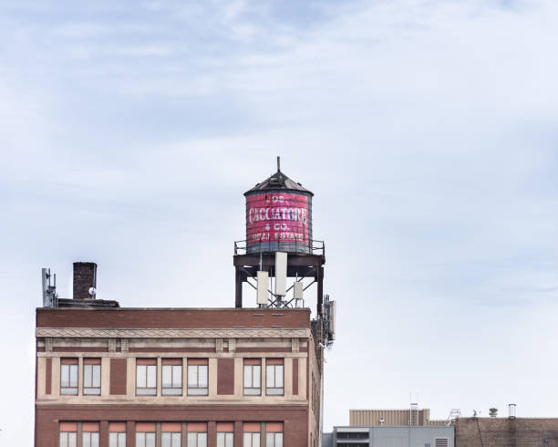 Red and white Salvation Army sign painted on side of four-story brick building and water tower, Chicago, with autumn tree and high rise building in background. stock photo