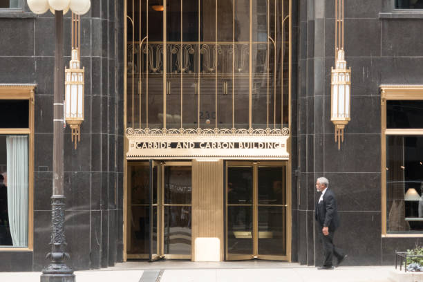 Close-up of the entryway to the Carbon and Carbide Building, Chicago, with revolving doors and walking pedestrian. Gray stone with gold gilding. stock photo