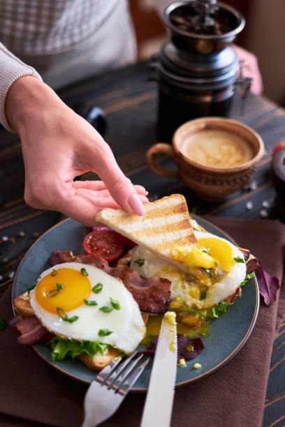 istock Tasty breakfast - fried egg toasts, bacon, tomatoes on wooden kitchen table 1474340602