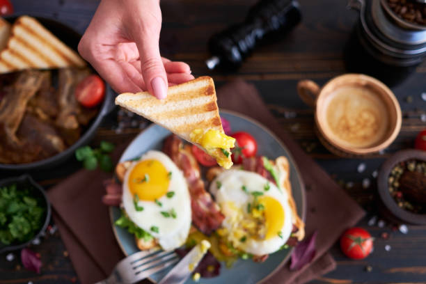 istock Tasty breakfast - fried egg toasts, bacon, tomatoes on wooden kitchen table 1474340605