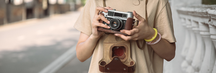 woman holding vintage camera in street background