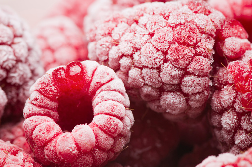 Studio close-up of frozen raspberries with a layer of frost covering them.