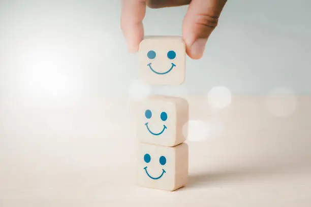 Photo of Mental health and emotional condition concept, choice of a positive mindset shown by a smiling face on the bright side of a wooden block cube.