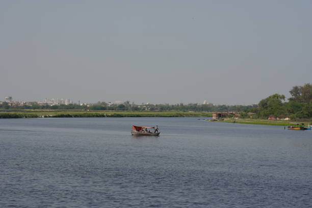 ein boot, das allein im teich schwimmt, fernsicht yamuna river ghat in vrindavan - yamuna river stock-fotos und bilder