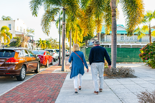 Naples, USA - January 29, 2021: Old town Naples, Florida downtown on Third Street South shopping district with candid senior couple walking on sidewalk at sunset