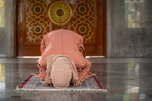 young muslim woman in hijab sitting in the mosque praying