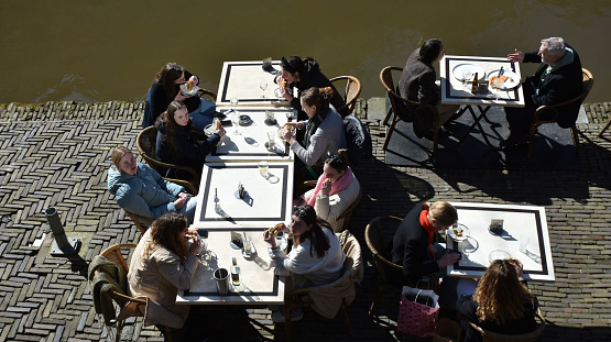 Utrecht City Canal In The Netherlands Europe, People Sitting Down, Talking To One Another, Eating And Drinking In A Restaurant Scene During Winter Season