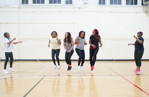 Middle Age African-American (Black) Women exercising by jumping rope in a gym