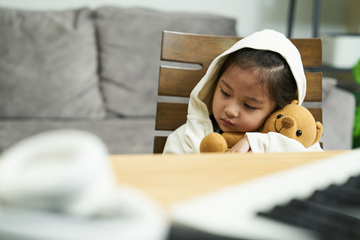 Asian girl having a music lesson but feels unwell at home