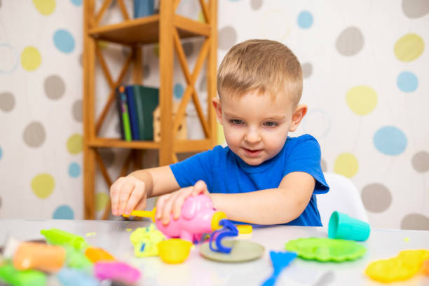istock Cute child sitting at the table and plays with playdough 1474360301