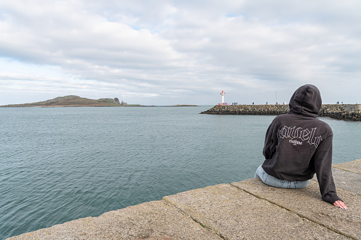 Girl looking at Howth Lighthouse on the East Pier from the West Pier with Ireland's Eye island in the distance, Howth Ireland