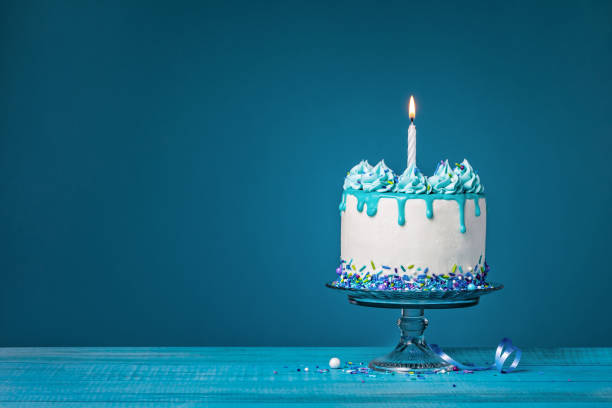 istock White cake with one lit birthday candle on a blue background 1474361624
