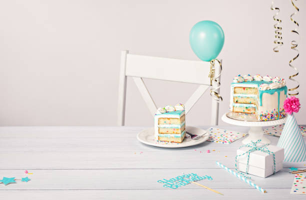 istock Birthday party table setting with slice of vanilla confetti cake and decorations on a light grey white background 1474361644