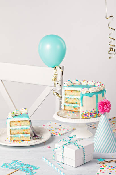istock Birthday party table setting with slice of vanilla confetti cake and decorations on a light grey white background 1474361847