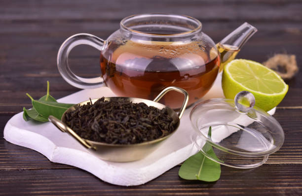 istock Tea in a transparent teapot on a white wooden board. 1474362873