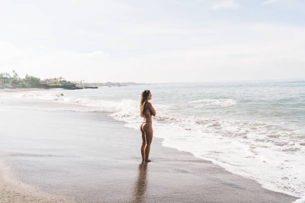 istock Woman standing on beach and looking at sea 1474363034