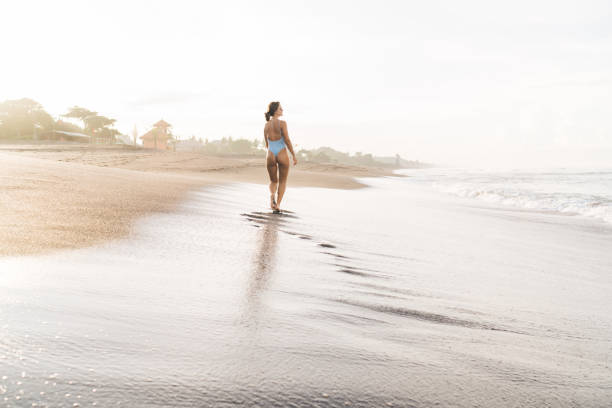 istock Slender woman walking on wet sandy seacoast 1474363037