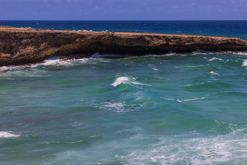 Beautiful view of waves of Atlantic Ocean breaking on rocky shore. Aruba.