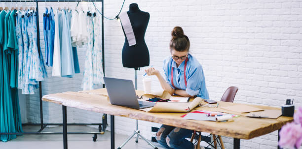 istock Young fashion designer thinking about new project sitting at table in workshop 1474377751