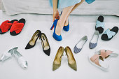 Unrecognizable female choosing shoes in modern studio
