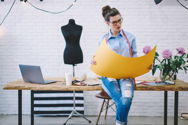 istock Concentrated female seamstress sitting with pattern in atelier 1474377765