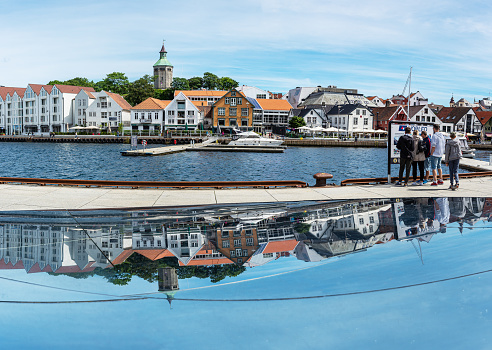 Stavanger, Norway - July 10, 2022: Old historical wooden houses in Stavanger at the Skagenkaien along harbour bay Vågen and the reflections in a glass object.