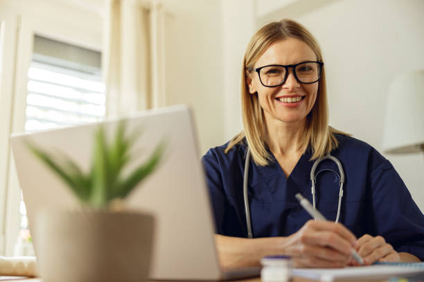 istock Female healthcare worker doing some paperwork and using laptop while working at doctor's office 1474378233