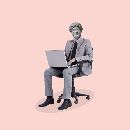 Contemporary art collage of a man headed by a statue head sitting on an office chair with a laptop. Concept of business, finance, economy, professionalism and success. Copy space.