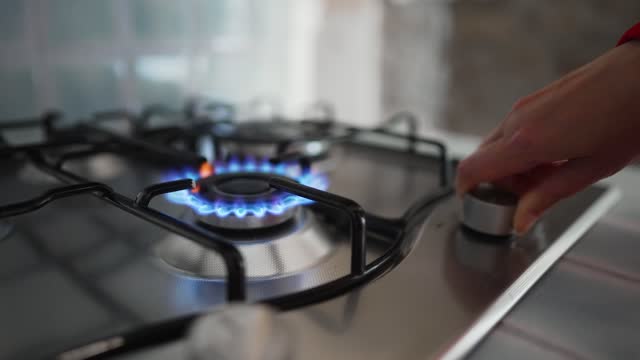 Woman turning on the gas burner on the stove.