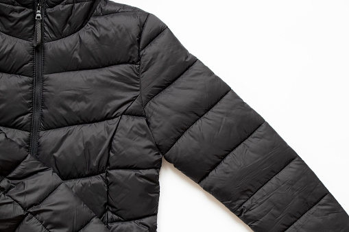Black puffy winter jacket lies on a white background, clothes