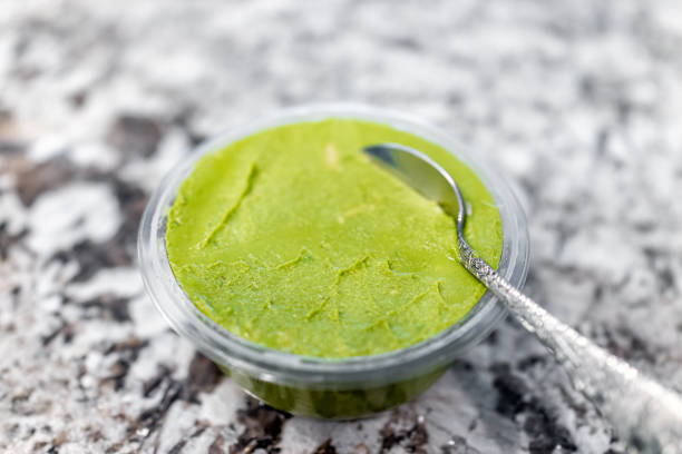 istock Plastic container bowl of organic green guacamole classic plain flavor with spoon serving closeup macro made from mashed avocados 1474389556