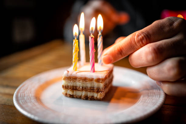 фра�нцузский наполеанский торт ломтик бокового вида крупным планом на белой тарелке, покрытой кремом, и вручную зажигая свечи на день рожде� - napolean стоковые фото и изображения