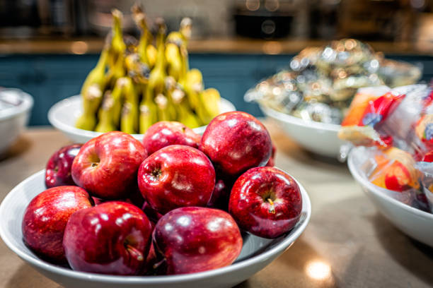 buffet di frutta fresca all'interno dell'hotel o del motel per la colazione continentale del mattino con deliziose mele rosse in ciotola e banane con muffin - muffin freedom breakfast photography foto e immagini stock