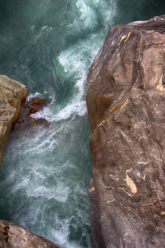 El río áspero de la montaña se funde en el abismo entre enormes rocas photo