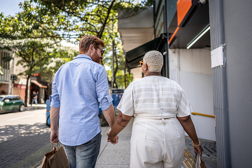 Rear view of a mature couple walking with shopping bag outdoors