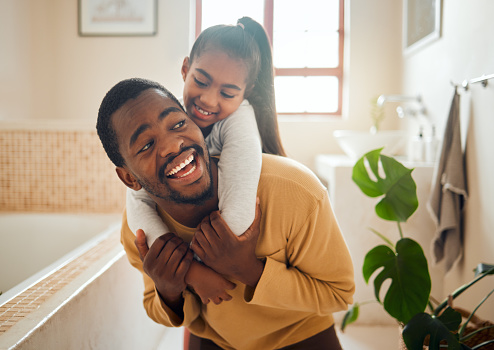 Black family, father and child in a happy home with love, care and support while in bathroom. Man and girl kid for a piggy back ride with a smile, energy and hug for safety, health and wellness