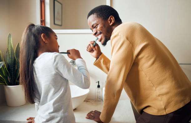 oral care, brushing teeth and father with daughter in bathroom for hygiene, grooming and bonding. dental health, girl and black people cleaning while having fun, playful and smile in their home - offspring child toothy smile beautiful imagens e fotografias de stock