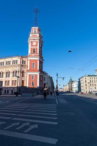 Russia, Saint Petersburg - February 27, 2022: Crosswalk on Nevsky Prospekt in the early winter morning next to red clock tower of old City Duma building. Soft focus. Travel in Russia theme.