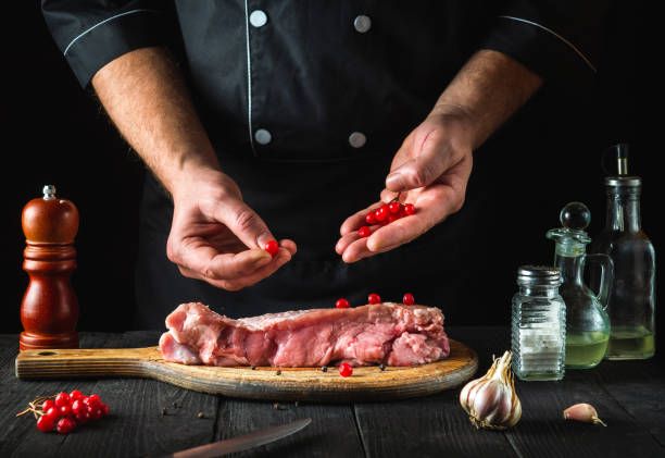 dans le restaurant, le chef de cuisine prépare de la viande de veau crue. avant la cuisson, le cuisinier met la viorne sur le bœuf. plat national - veal calf meat baking photos et images de collection