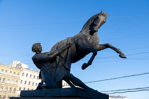 Close-up view of Horseman statue of Anichkov Bridge on Fontanka river on Nevsky Prospekt in the early winter morning in Saint Petersburg. Clear blue sky. Selective focus. Russian architecture theme.